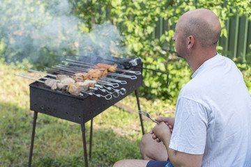 Man cooking meat on barbecue. Young couple making barbecue in their garden. Man cooking meat on barbecue