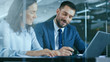 © Gorodenkoff - Female Accountant and Male Businessman Sitting at the Desk Having Discussion and Working on a Desktop Computer, Solving Problems. Modern Stylish Office with Beautiful People.