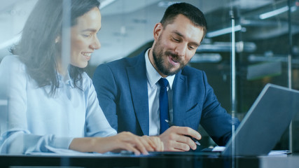 female accountant and male businessman sitting at the desk having discussion and working on a deskto