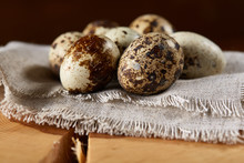 Quail Eggs Arranged In Circle On A Napkin On A Log Over A Wooden Background, Close-up, Selective Focus.