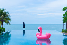 Flamingo Raft Floating In Swimming Pool In Front Of The Sea And Island