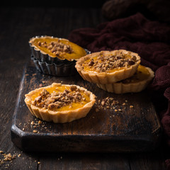 Wall Mural - Pumpkin mini pie, tartlet made for Thanksgiving day on old wooden background. Healthy autumn food concept with copy space. Dark photo.