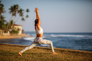 Wall Mural - Caucasian woman practicing yoga at seashore of tropic ocean