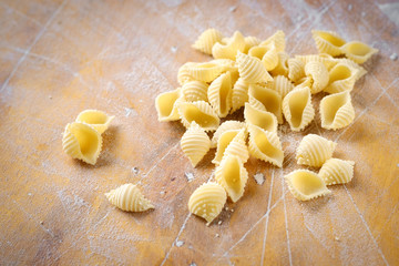 Wall Mural - fresh conchiglie pasta on a wooden table with flour