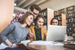 © Yakobchuk Olena - Optimistic girls and positive men working with laptop while sitting at table in library