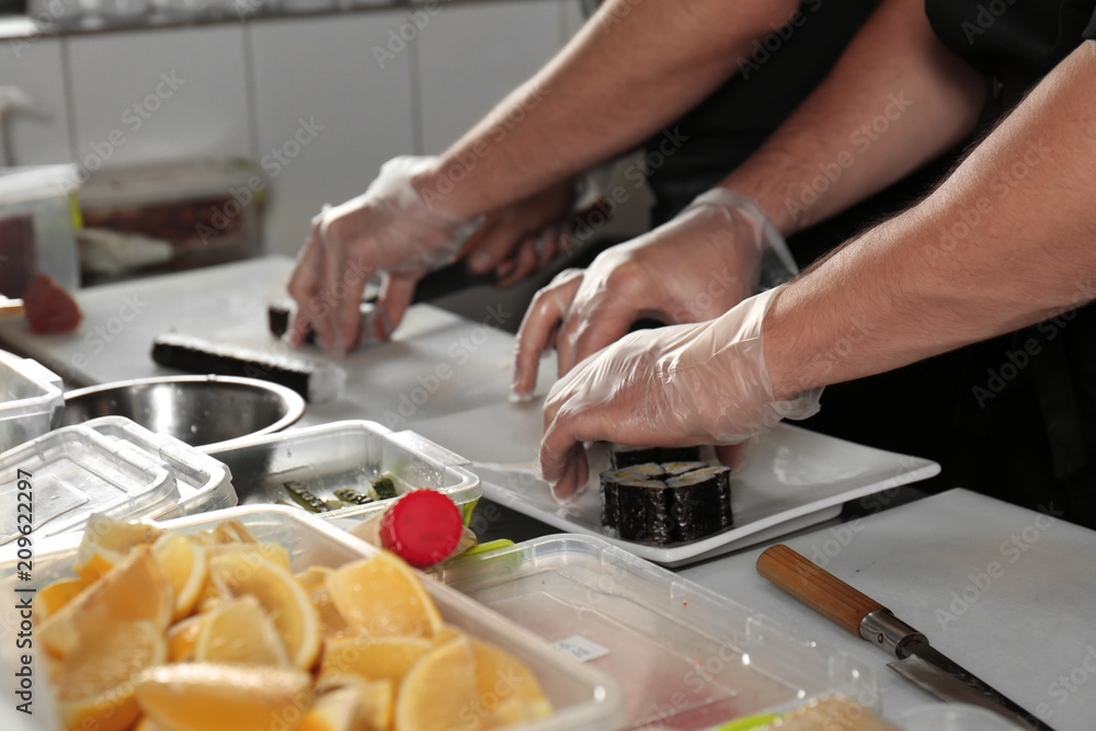 Chef making tasty maki rolls in restaurant