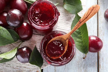 Wall Mural - Glass jars with delicious plum jam on wooden background