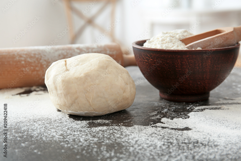 Raw dough with flour on table