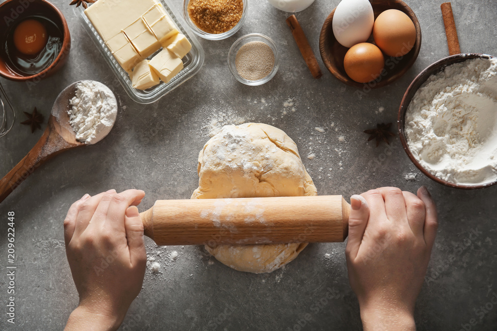 Woman rolling dough on table, closeup
