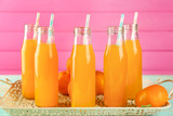 Bottles with fresh citrus juice on tray