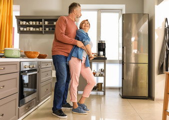 Poster - Happy mature couple dancing in kitchen