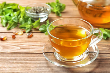 Cup with hot aromatic mint tea on wooden table