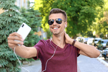 Wall Mural - Young man in sunglasses taking selfie outdoors