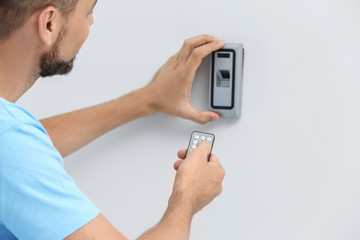 young male technician programming alarm system indoors