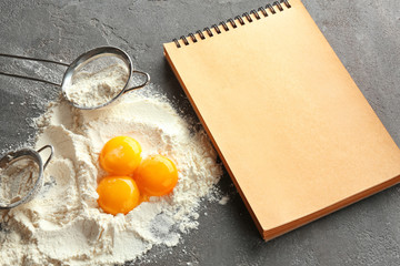 Notebook and products for making bread on grey background