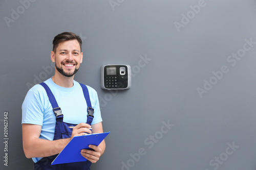 Fotomural Male technician with clipboard near installed alarm system indoors