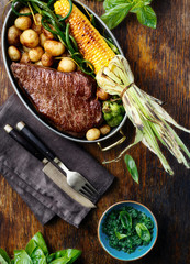 Poster - juicy beef steak in frying pan with vegetables top view