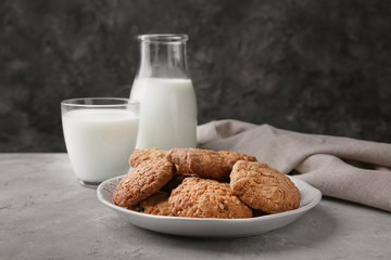 Plate with delicious oatmeal cookies and milk on table