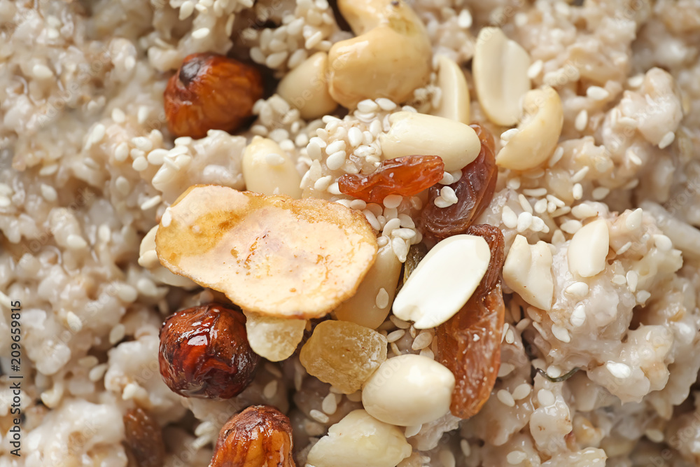 Tasty oatmeal with raisins and nuts, closeup
