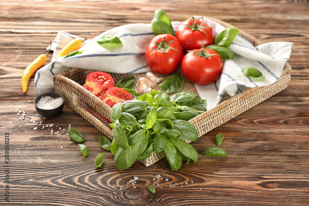Wicker tray with fresh vegetables and spices on wooden background