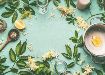 Elder flowers  cooking preparation. Frame of Elder flowers with spoon, pot, sugar and lemon on blue table background, top view