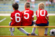 © matimix - Football soccer children team. Kids substitute players sitting on a bench. Football sports tournament for young boys. Three kids watching football game on a pitch