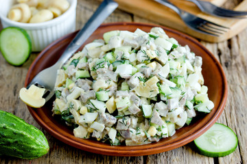 Wall Mural - Meat salad with fresh cucumber, marinated mushrooms, boiled eggs and dill in clay plate on wooden background