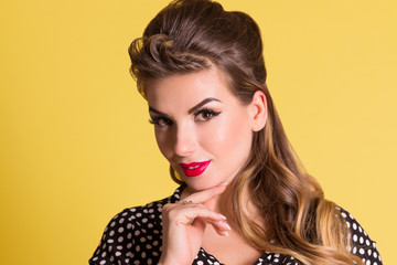 Pretty woman with make up poses in yellow studio, pin up style