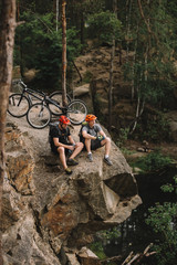 high angle view of happy young trial bikers relaxing on rocky cliff after ride