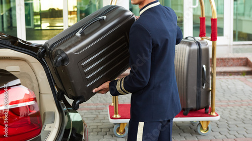 Fotografía Bellboy taking baggage of guest from thee car to his room