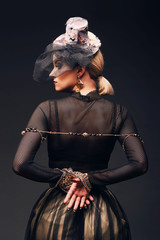 Sensual woman in rock baroque style; dressed in black perforated fabric and bondaged with jewelrys