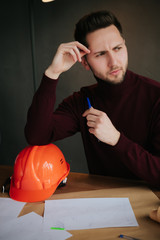 Male engineer holding a safety hat and a construction model.