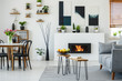 © Photographee.eu - Black chairs at dining table with flowers in flat interior with grey sofa next to fireplace. Real photo