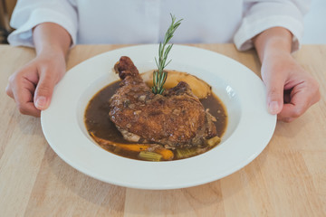 Closeup image of woman holding a plate of slow cooker chipotle chicken stew on wooden table