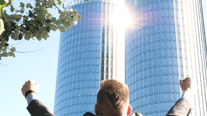 Successful businessman in suit, feels free, skyscraper background. Concept: success, career growth, victory, freedom.