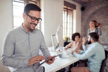 Smiling young man using digital tablet in the office