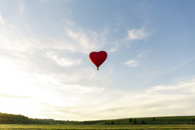 Red Hot Air Balloon In The Shape Of A Heart Fly In Sky. Love, Honeymoon And Romantic Travel Concept
