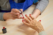 © DenisProduction.com - Beautician applying red varnish to woman nails. Manicurist painting nails to elderly woman with red polish on salon table. Old woman receiving manicure.