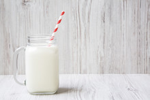 Side View Of Jar Of Cold Milk On A White Wooden Background. Closeup. Copy Space.