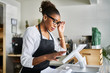 © Joshua Resnick - shop assistant placing order from notepad into pos point of sale terminal at register in restaurant