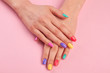 Female hands with colorful polish nails. Woman well-groomed hands with multicolor nails on salon table. Manicure nail painting.