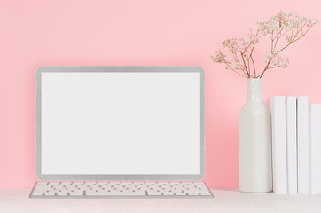 Modern fashion workplace - silver laptop with blank screen, white stationery, books on soft pink background.