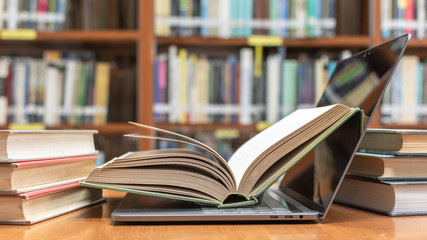 E-learning class and e-book digital technology in education concept with pc computer notebook open in blur school library or classroom background among old stacks of book, textbook archive collection