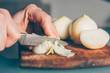 © andrey gonchar - The cook cuts the onion on a cutting board