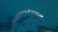 Aerial View Of A White Motorboat Running On The Azure Waters Of The Tyrrhenian Sea. On His Trip Near The Coast The Boat Leaves A White Trail In The Waves Ofeaves A White Trail In The Waves Of The Sea.