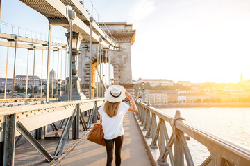 Canvas Print - Young woman traveler walking on the famous Chain bridge during the sunset in budapest, Hungary