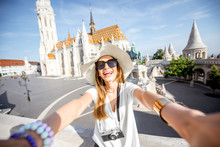 Young Woman Tourist Making Selfie Photo Standing In Front Of The Famous Mattias Church In Budapest, Hungary