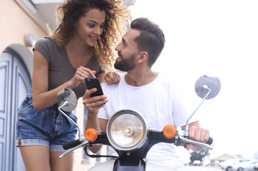 Happy young couple having summer trip on a scooter