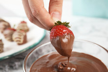Woman Dipping Ripe Strawberry Into Bowl With Melted Chocolate, Closeup