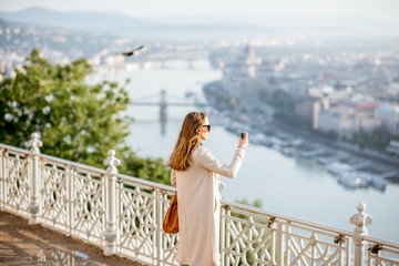 Wall Mural - Young woman photographing beautiful morning view on Budapest city from the Gellert hill in Hungary